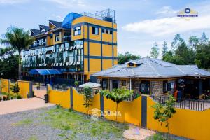 a yellow building with a house in front of it at The Grand Brystal Hotel in Busia
