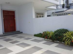 a white building with a red door and some plants at Borey Villa Toulsangke in Phnom Penh