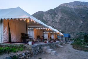 a tent with chairs and a mountain in the background at Camp The Sanga Manali in Tāndi