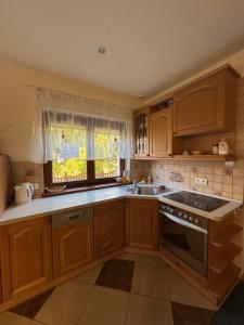 a kitchen with wooden cabinets and a sink and a window at Domek nad jeziorem Mierzyńskim 50m2 in Mierzyn