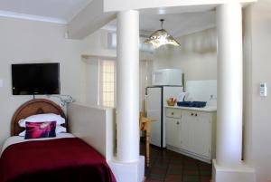 a room with a bed with columns and a kitchen at Dias Guest House in Bloemfontein