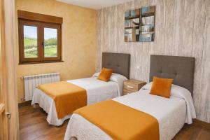a room with two beds with orange and white sheets at El Carloto Lanchares in Lanchares