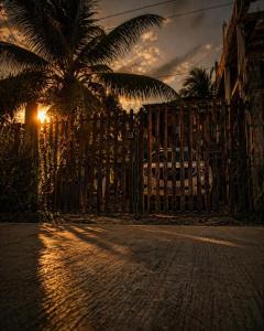 a fence with a palm tree in front of the sunset at El coltejeriano in Coveñas