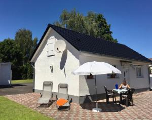 a woman sitting at a table in front of a small house at Ferienhaus Schmidt in Storkow