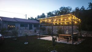 a pergola with a wooden table in a yard at Stone House Montenegro in Danilovgrad