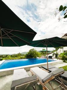 a pool with a green umbrella and some chairs and a table at Garden Hill Views in Kuta Lombok