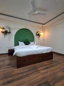 a bedroom with a large bed with a green headboard at Temple Tree Homes in Bangalore