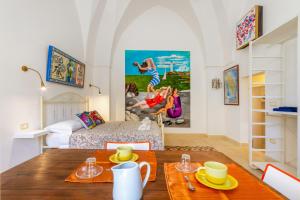 a living room with a table and a bedroom at GuestHost - Arkè Colorful Apartment in Giuggianello