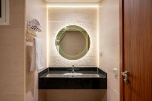 a bathroom with a sink with a round mirror at Atlantic Blue 3BR Ocean View, Rabat Corniche in Rabat +37 photos