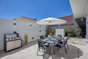 a patio with a table with chairs and an umbrella at 6BR luxury villa with Pool & Hot tub - 2Living rooms & 10Bathrooms in Tal-Għoqod