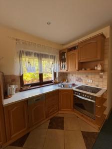 a kitchen with wooden cabinets and a sink and a window at Domek nad jeziorem Mierzyńskim 50m2 in Mierzyn +4 photos
