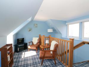 a living room with blue walls and chairs and a staircase at Post Cottage in Arisaig