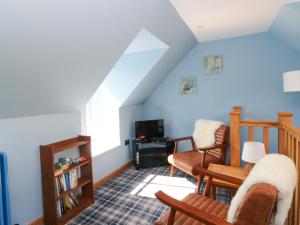 a living room with blue walls and a couch and chairs at Post Cottage in Arisaig