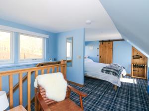 a bedroom with blue walls and a bed and a balcony at Post Cottage in Arisaig