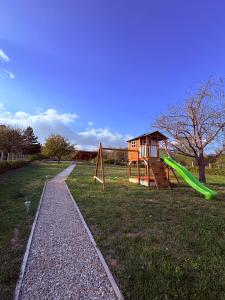 a playground with a green slide and a house at Haptapta House in Balatonudvari