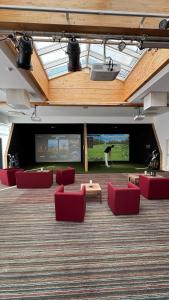 a large room with red chairs and a large screen at DAS LUDWIG Sports Resort in Bad Griesbach