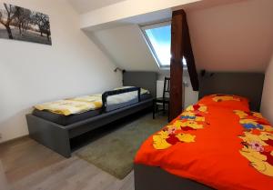 a bedroom with a bed with an orange comforter and a window at Ferienwohnung auf Vierseitenhof in Senftenberg