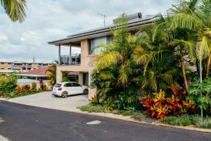 a white car parked in front of a house with palm trees at Coffs Jetty BnB in Coffs Harbour