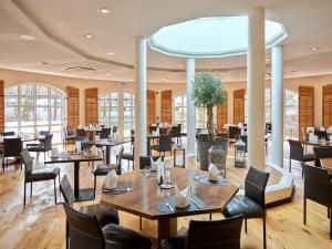 a dining room with tables and chairs and windows at DAS LUDWIG Sports Resort in Bad Griesbach