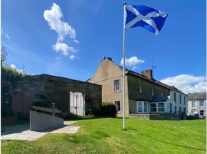 a flag on a pole in front of a house at Borders Cottage in Coldstream