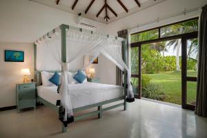 a bedroom with a canopy bed and a large window at Ranna Beach House in Ranna
