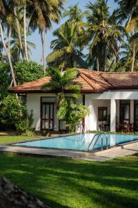 a house with a swimming pool and palm trees at Ranna Beach House in Ranna