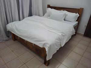 a large bed with white sheets and pillows at Olulu Place in Frere Town