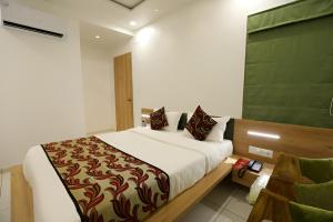 a bedroom with a large bed and a chair at Nova Yashraj Hotel in Rajkot