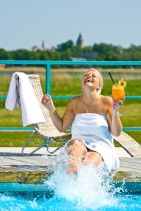 Una donna seduta in piscina con un drink di Fra Mare Thalasso Spa a Haapsalu
