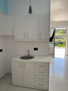 a kitchen with white cabinets and a sink at Hotel Irini in Sarandë