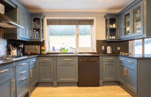a kitchen with blue cabinets and a sink and a window at Skeabost View in Tole
