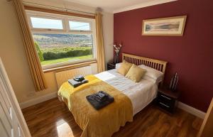 a bedroom with a bed with a yellow blanket and a window at Skeabost View in Tole