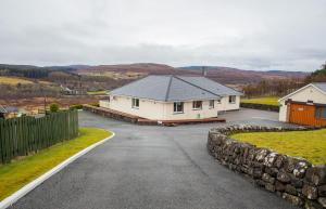 a house on a road with a stone wall at Skeabost View in Tole