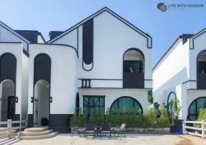 a white house with black windows and chairs at Live With Passion Pool Villa in Pak Chong