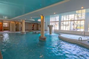 a large swimming pool in a building with columns at Pegasa Pils Spa Hotel in Jūrmala