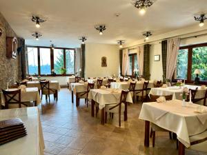 a restaurant with white tables and chairs and windows at Hotel Dwór Karolówka in Zakopane