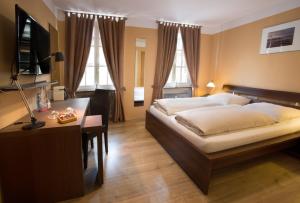 ein Schlafzimmer mit einem Bett, einem Schreibtisch und Fenstern in der Unterkunft Stadthotel Jülich in Jülich