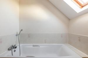 a white bathroom with a bath tub with a skylight at 4 Bed in Westward Ho oc-n1623 in Westward Ho +19 photos