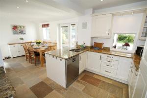 a kitchen with white cabinets and a dining room with a table at 4 Bed in Swansea oc-hh682 in Parkmill