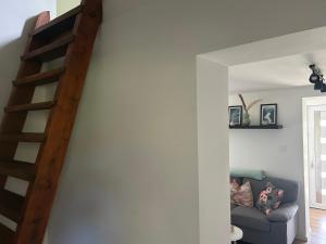 a living room with a staircase and a couch at Bazsarózsa Kuckó in Pécsvárad +5 photos