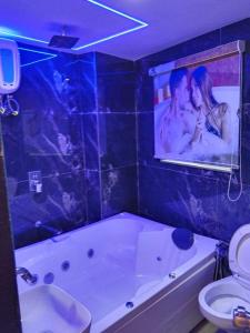 a bathroom with a tub and a picture of a couple at Hotel Bellemount in Ahmedabad