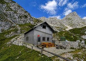 a small building on a mountain with a table and benches at Zavetišče pod Špičko in Soča