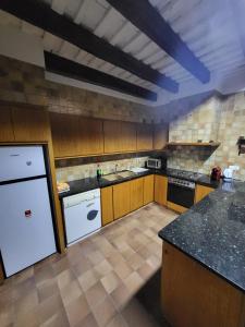 a large kitchen with wooden cabinets and white appliances at Can Cuti in Santa Eulalia de Ríuprimer