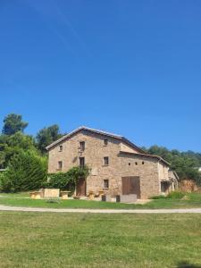 an old stone building sitting on a grass field at Can Cuti in Santa Eulalia de Ríuprimer