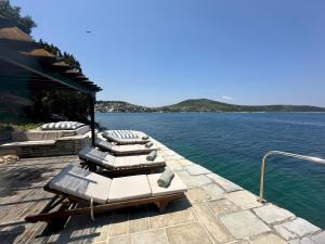a row of lounge chairs on a dock on the water at Villa Mitzela in Amaliapoli +45 photos