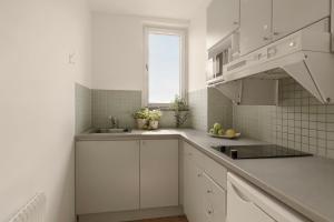 a white kitchen with a sink and a window at The Nooq Alvik - Hotel & Studios in Stockholm