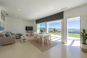 a living room with a table and chairs at Villa Las Palmeras Valdevaqueros Suites, Pool & Sea Views in Tarifa