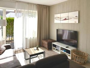 a living room with a television and a couch at Luxe Duinsuite in Groet