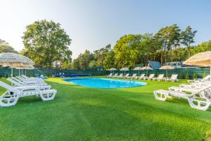 a group of lawn chairs and a swimming pool at Bursztynowo Mikoszewo in Mikoszewo