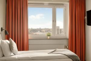 a bedroom with a window with orange curtains and a bed at The Nooq Alvik - Hotel & Studios in Stockholm